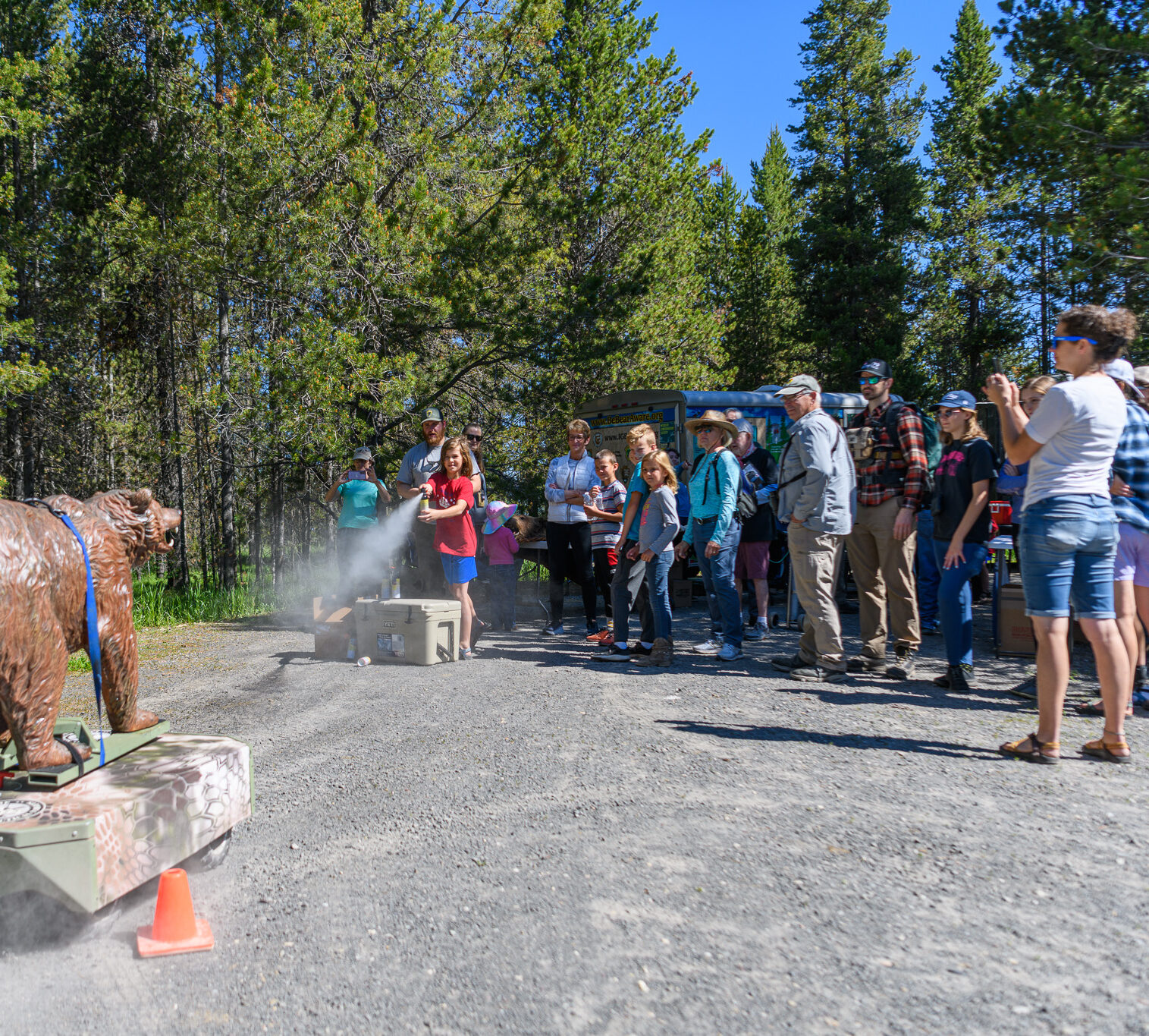 Group watches as child practices using bear spray with a mechanical bear